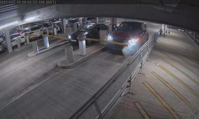 The Red Range Rover Sport arriving at the ticket barrier, with light smoke coming from the vehicle