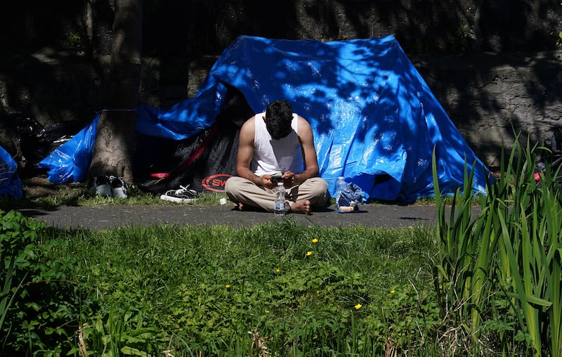 A man sits outside one of the dozens of tents