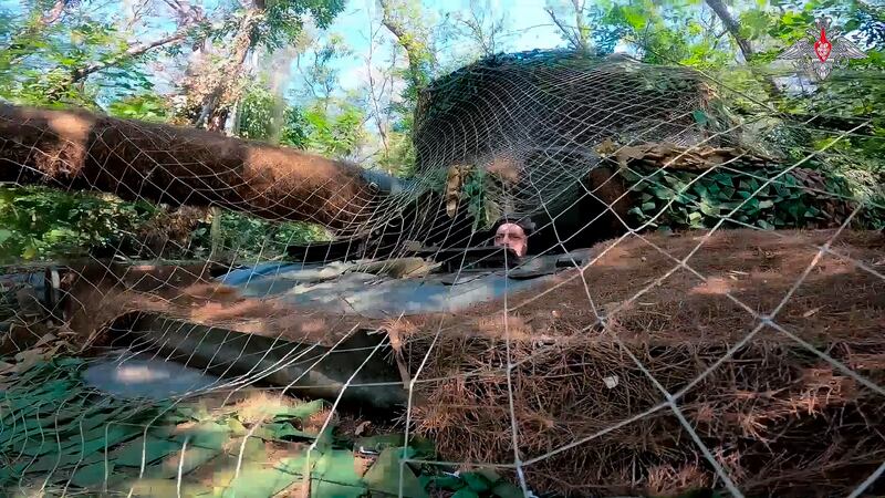 A Russian army tank covered with camouflage net takes a position in the Kursk region (Russian Defence Ministry Press Service/AP)