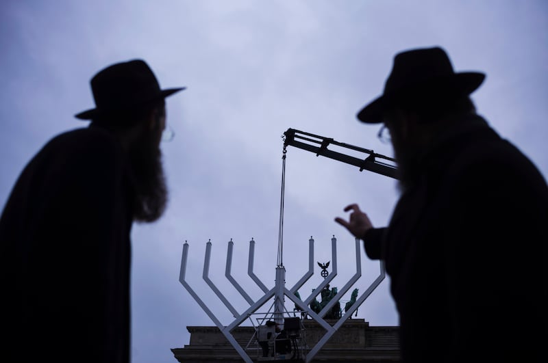 Rabbi Yehuda Teichtal, right, and Rabbi Shmuel Segal, left, watch the set-up of a giant Hanukkah Menorah by the Jewish Chabad Educational Centre in front of the Brandenburg Gate in Berlin (AP Photo/Markus Schreiber)