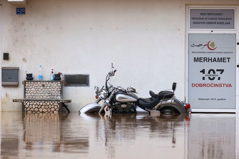 A motorcycle is partially submerged in floodwaters outside an apartment building in the village of Kiseljak, northern Bosnia (Armin Durgut/AP)