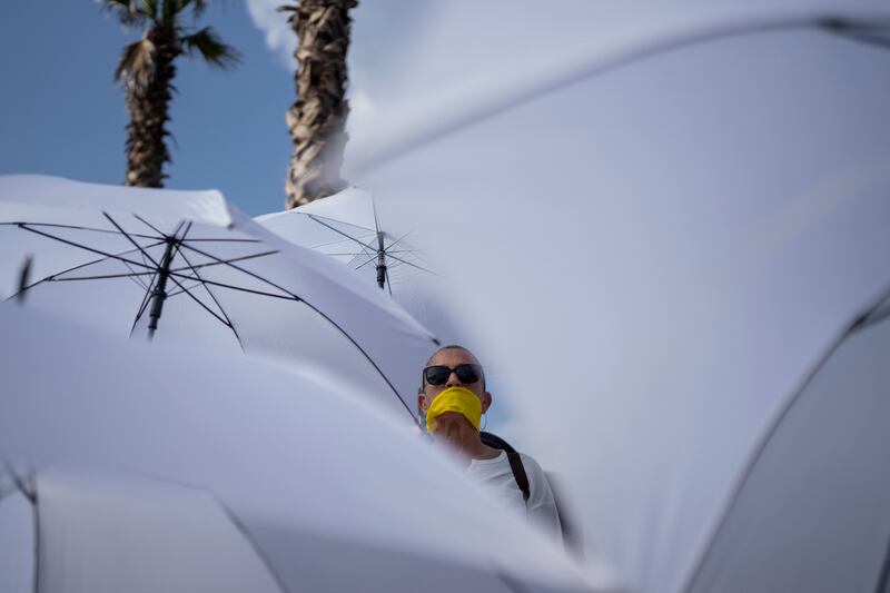 An activist with a yellow ribbon on her mouth holds a white umbrella during a protest calling for the release of hostages held in the Gaza Strip (Oded Balilty/AP)