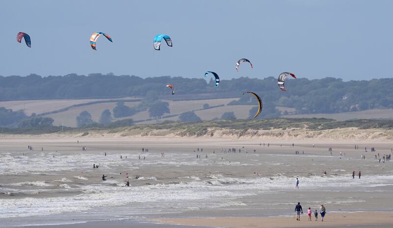 Kite surfers enjoy the windy conditions on the sea at Camber Sands in East Sussex on Sunday