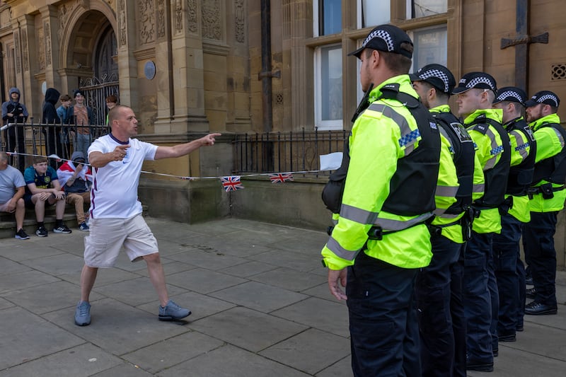 Roger Haywood stands in front of a line of police