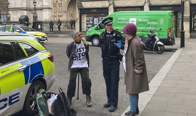 Just Stop Oil protesters Di Bligh, 77, and Alyson Lee, 66, with a police officer outside Westminster Abbey in central London after they spray painted “1.5 is dead” on the grave of Charles Darwin