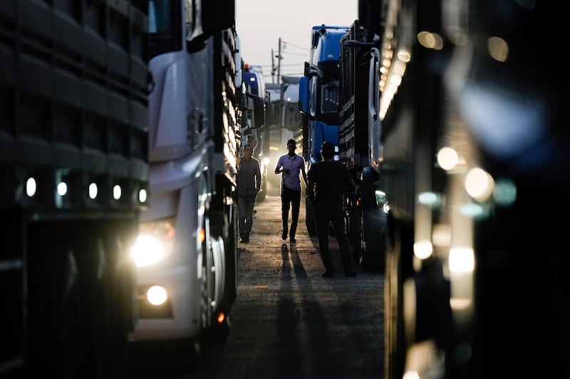 A truck driver walks between trucks carrying humanitarian aid just before they cross into the Gaza Strip in southern Israel (AP Photo/Tsafrir Abayov)