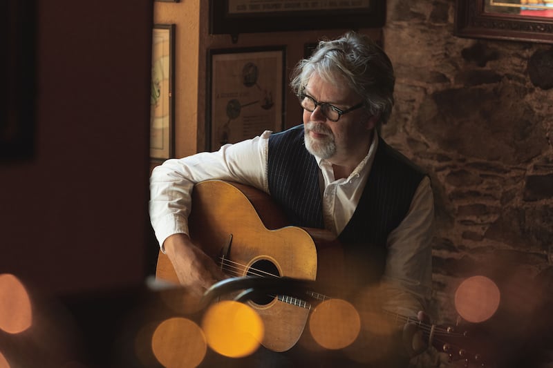 A photo of Anthony Toner playing his acoustic guitar