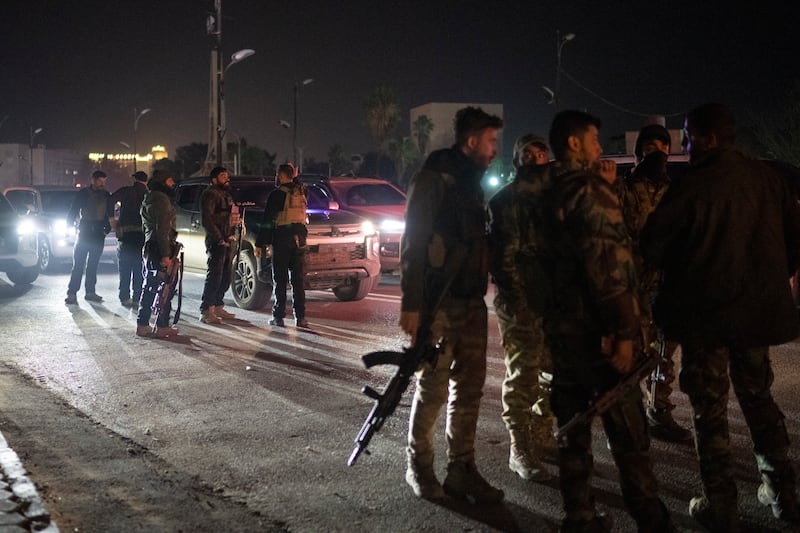 Syrian fighters gather during the night on a street in Damascus (Leo Correa/AP)