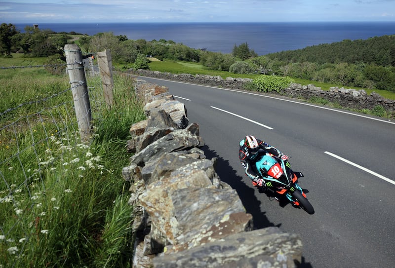 Peter Hickman riding a motorbike past sheetrock in the Isle of Man TT
