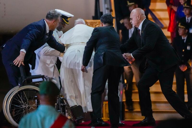 Papua New Guinea’s deputy prime minister John Rosso, right, and rear-admiral Philip Polewara, second from left, reach out to help Pope Francis keep his balance during a welcome ceremony at Port Moresby’s Jackson International Airport on Friday (Gregorio Borgia/AP)