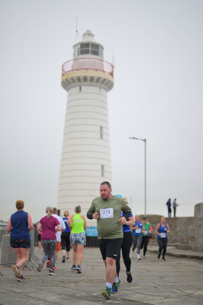 Group of runners in 5k race in front of white lighthouse