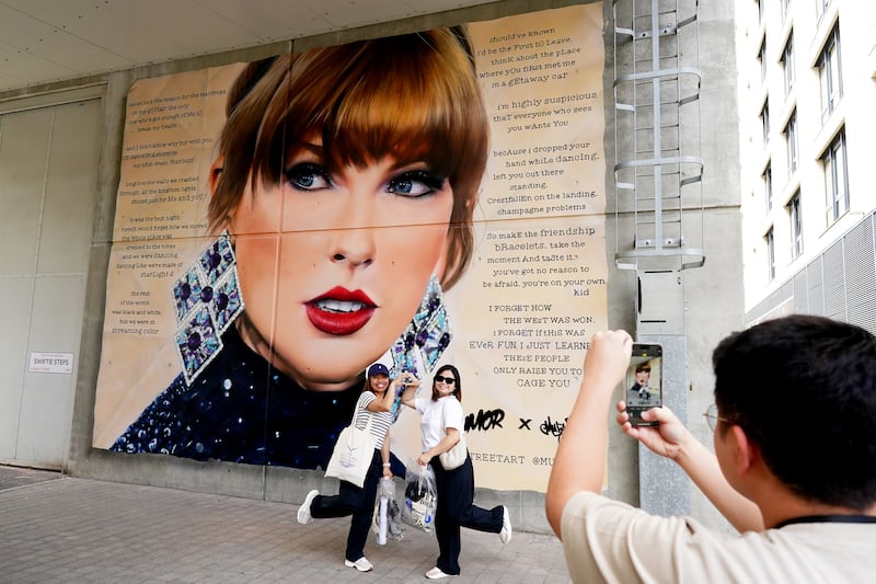 Fans pose for selfies in front of a mural of Taylor Swift outside Wembley Stadium