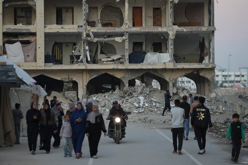 Palestinians walk past destroyed buildings in Khan Younis, Gaza Strip (Abdel Kareem Hana/AP)