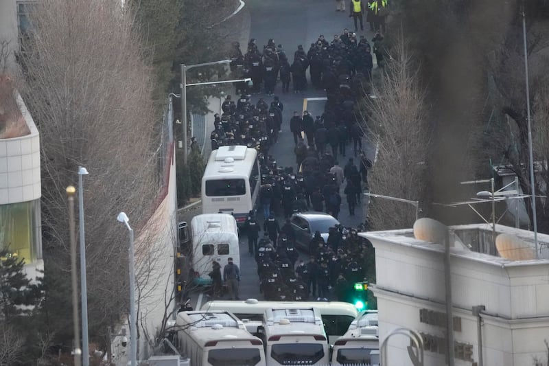 Investigators from the state anti-corruption agency and police officers make their way to the residence of impeached President Yoon Suk Yeol (Ahn Young-joon/AP)