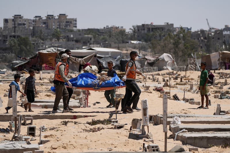 Workers carry a body to a cemetery in Khan Younis, Gaza Strip (Abdel Kareem Hana/AP)