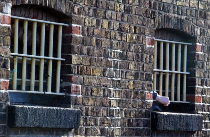 A prisoners hand pokes through the bars.