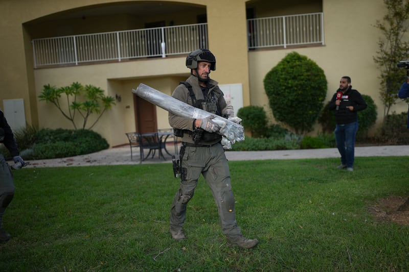 An Israeli bomb squad policeman in Kibbutz Kfar Blum, northern Israel, carries the remains of a rocket that was fired from Lebanon (Ohad Zwigenberg/AP)