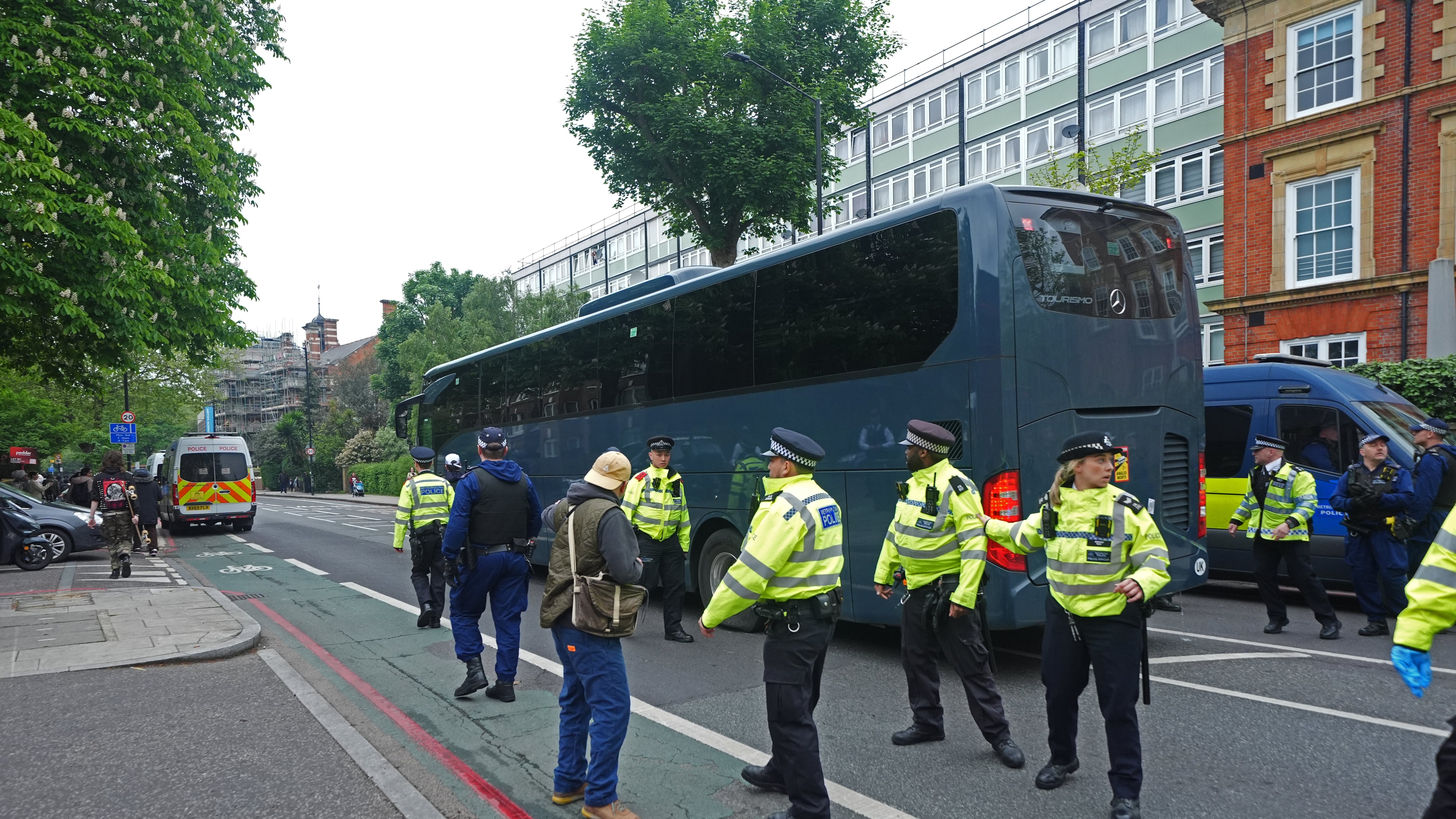 Police move protesters as the coach leaves after demonstrators formed a blockade around a it