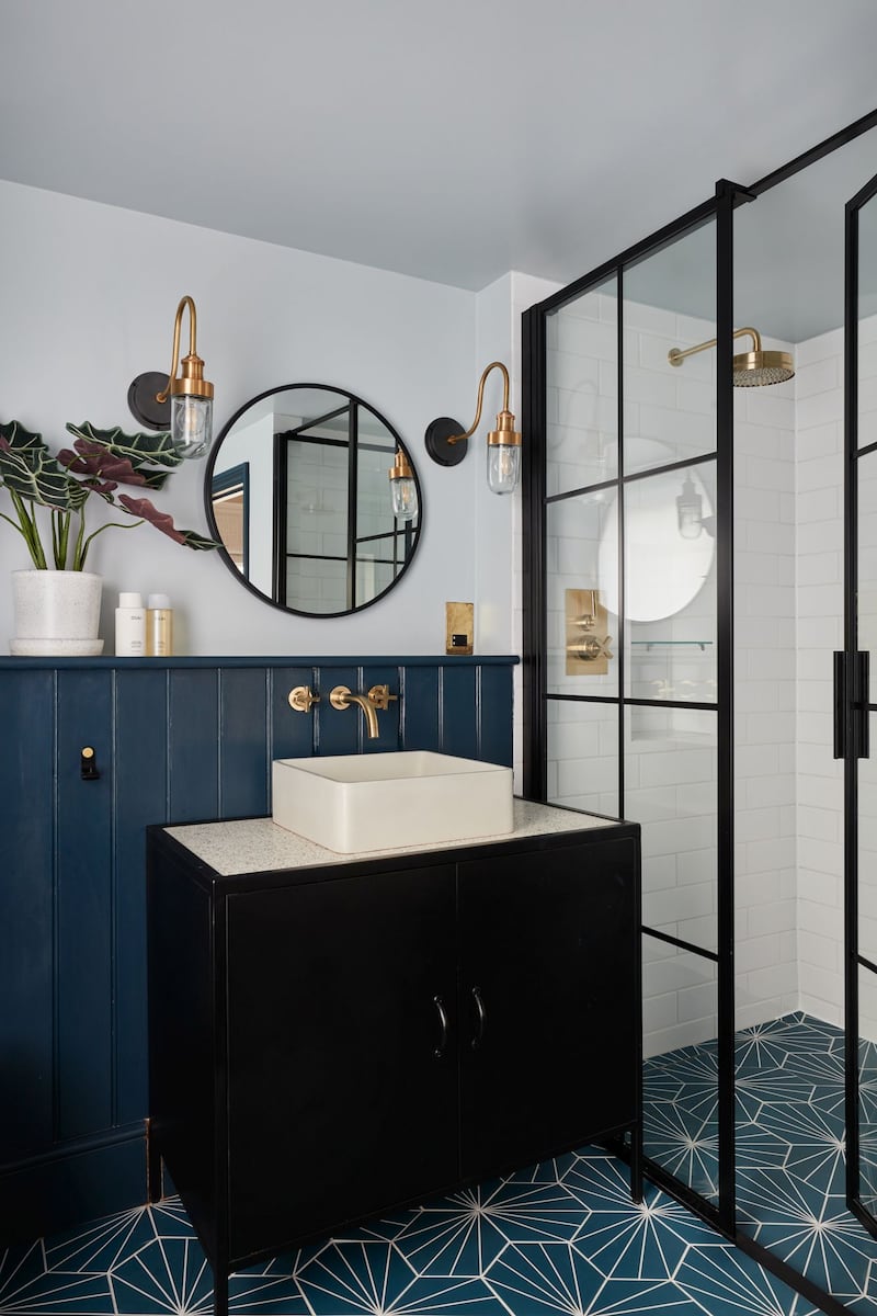 Stylish wall sconces add functional and ambient lighting to this transitional bathroom by Muchmore Design