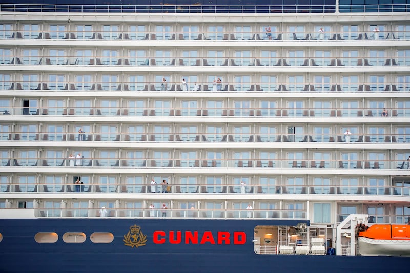 Passengers look out from their cabins on the Queen Anne ahead of the naming ceremony