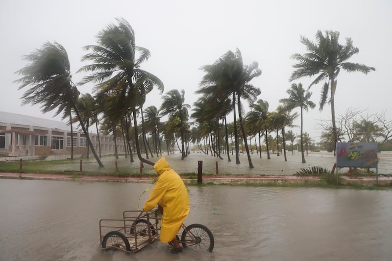 A person rides his bike through a flooded street in the rain as Hurricane Milton passes off the coast of Progreso, Yucatan state, Mexico (Martin Zetina/AP)