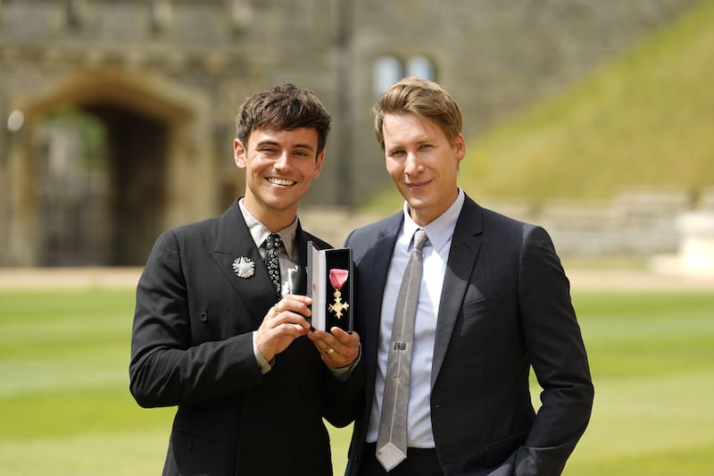 2JGNWN7 Tom Daley, and his husband Dustin Lance Black, with his OBE (Officer of the Order of the British Empire) for services to diving, as well as in recognition of his charity work and his support of LGBTQ+ rights following an investiture ceremony at Windsor Castle. Picture date: Tuesday July 12, 2022.