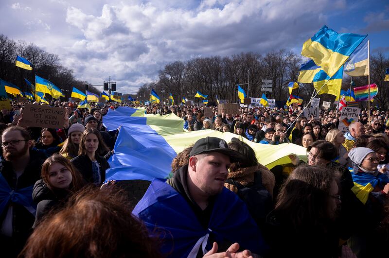 People hold a huge Ukrainian flag as they attend a protest against the Russian war in Ukraine in front of the Russian embassy in Berlin (Markus Schreiber/AP)