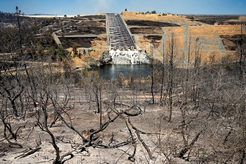 Water flows down the Oroville Dam spillway behind vegetation scorched in the Thompson Fire in Oroville, California (Noah Berger/AP)
