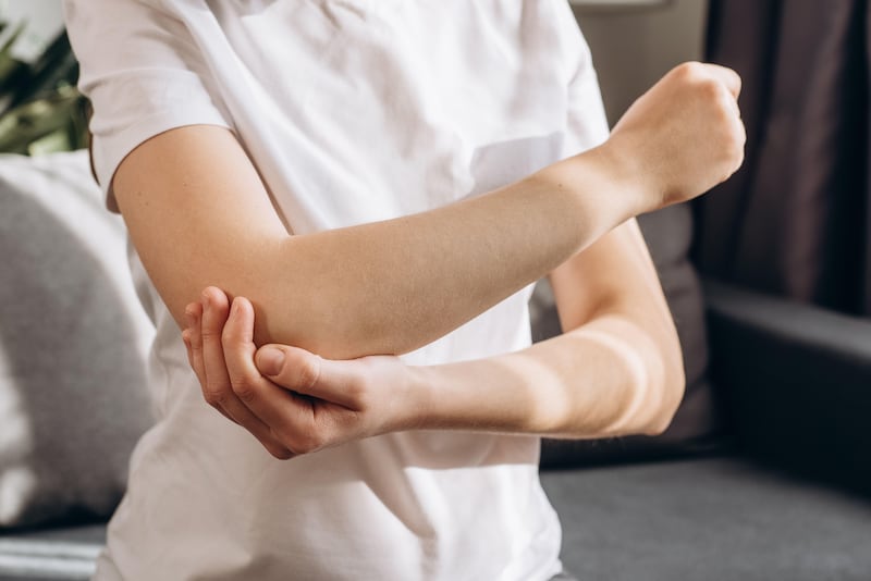 Close up of woman experiencing pain in her elbow holding her arm