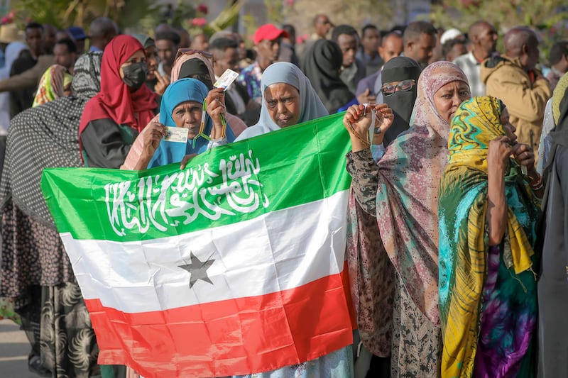 A woman held the Somaliland flag as people queued to cast their votes during the presidential election (Abdirahman Aleeli/AP)