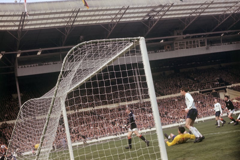 Denis Law celebrates scoring for Scotland against England .