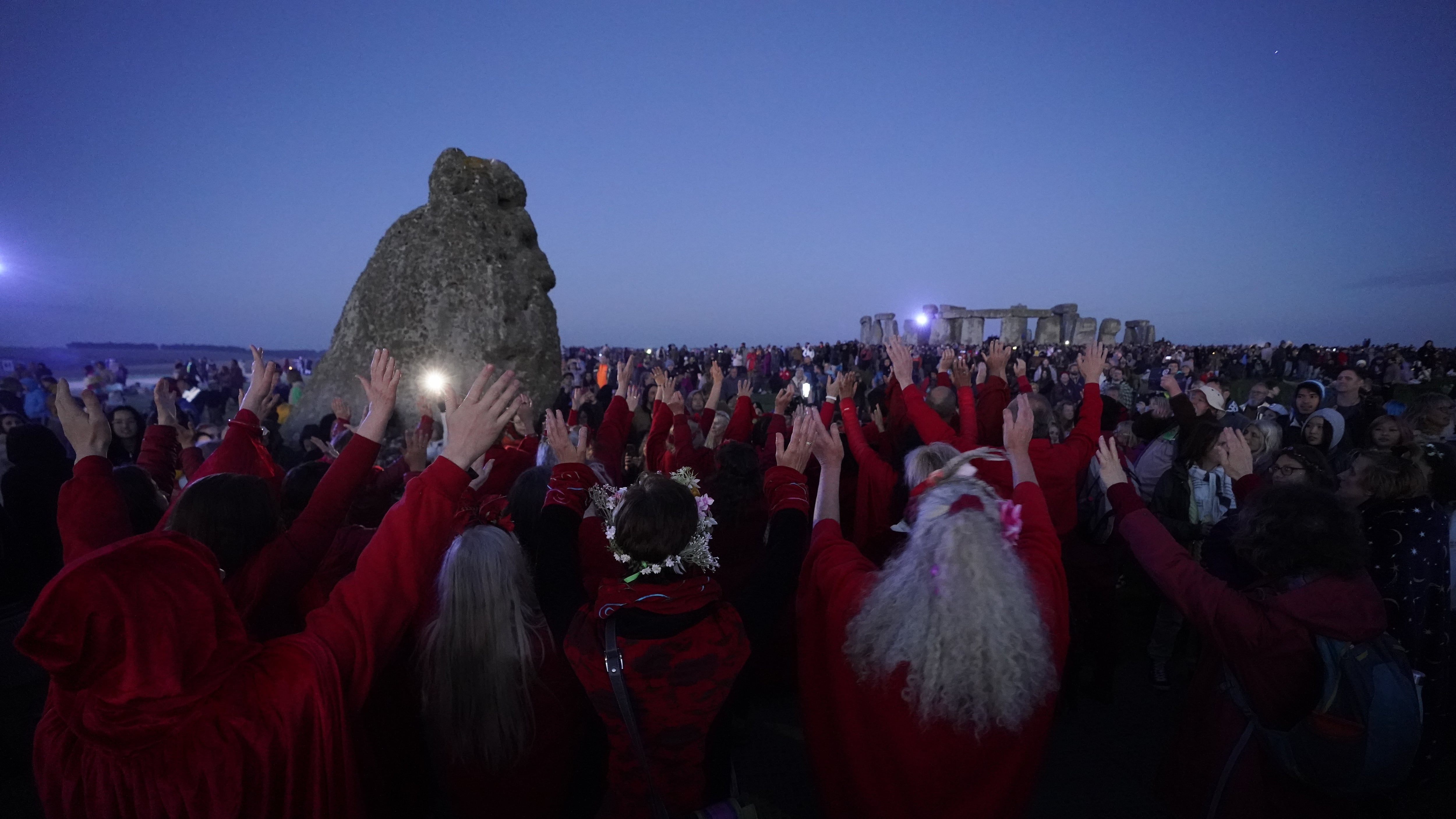 People watch the sun rise as they take part in the summer solstice at Stonehenge in Wiltshire