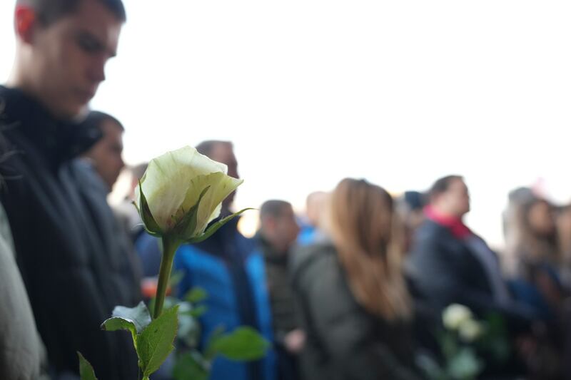 Students hold white flowers in front of the court building (Darko Vojinovic/AP)