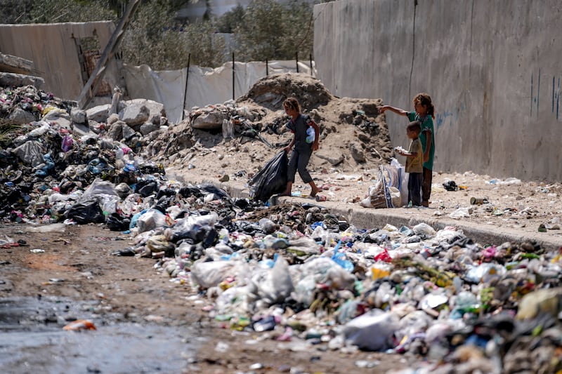 Displaced children sort through trash at a street in Deir al-Balah, central Gaza Strip (Abdel Kareem Hana/AP)