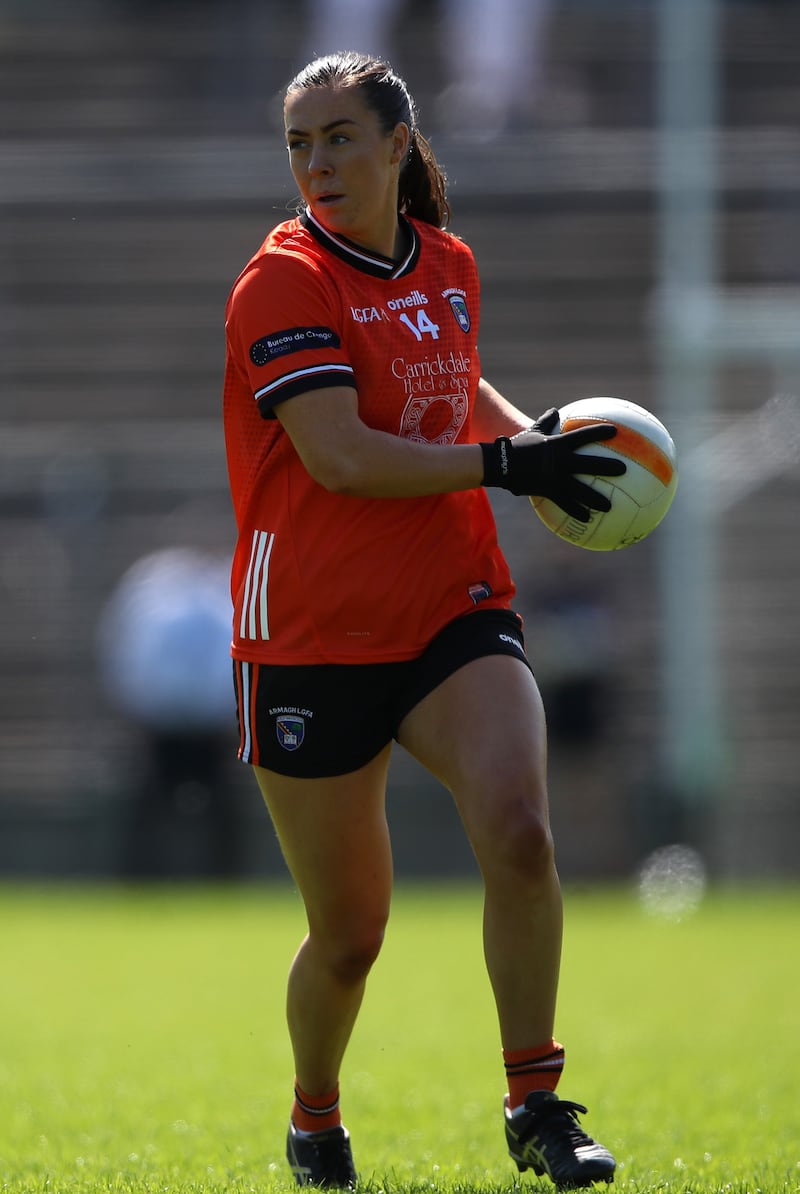 Niamh Henderson carrying a ball in an orange Armagh jersey