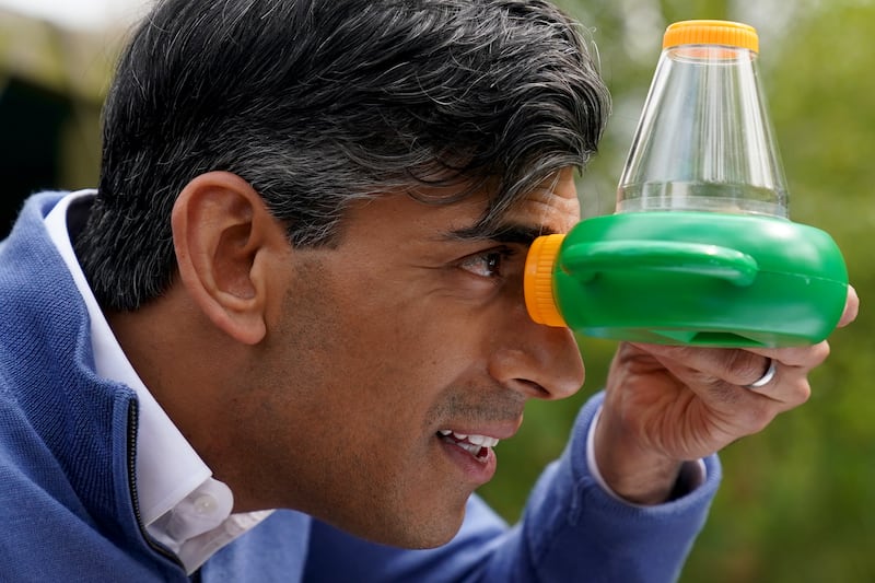 Prime Minister Rishi Sunak looks through a microscope while on the General Election campaign trail