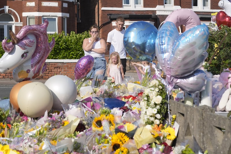 People look at floral tributes on Maple Street, Southport