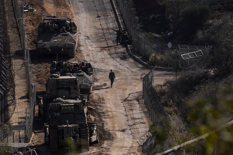 An Israeli soldier walks near armoured vehicles parked near the so-called Alpha Line that separates the Israeli-annexed Golan Heights from Syria (Matias Delacroix/AP)