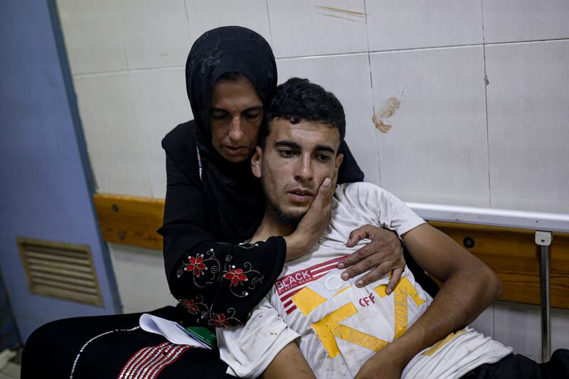 A Palestinian woman hugs her son at a hospital in Khan Younis after he was wounded in the Israeli bombardment of the Gaza Strip (Jehad Alshrafi/AP)