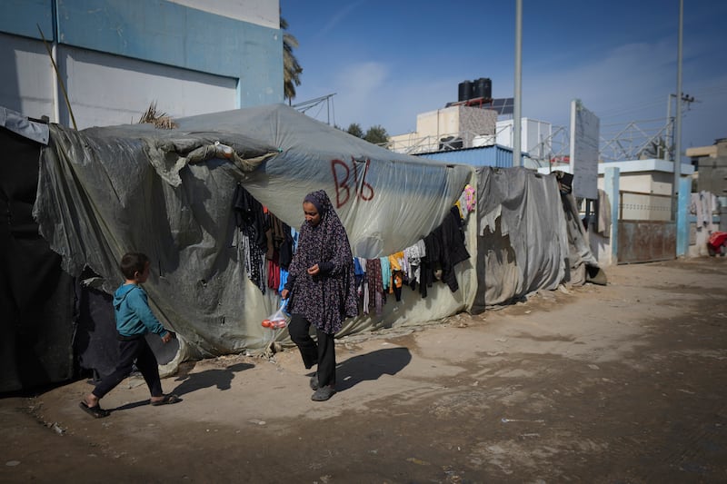 A woman and a child walk outside their tent at a camp for displaced Palestinians in Deir al-Balah, central Gaza Strip (Abdel Kareem Hana/AP)