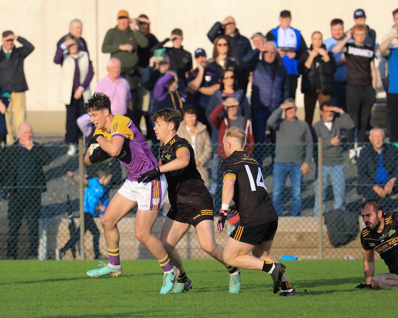 Derrygonnelly's Jarlath Flanagan keeps a tight grip on the ball in anticipation of a tackle from Dan McCann and Shane Rooney of Erne Gaels.