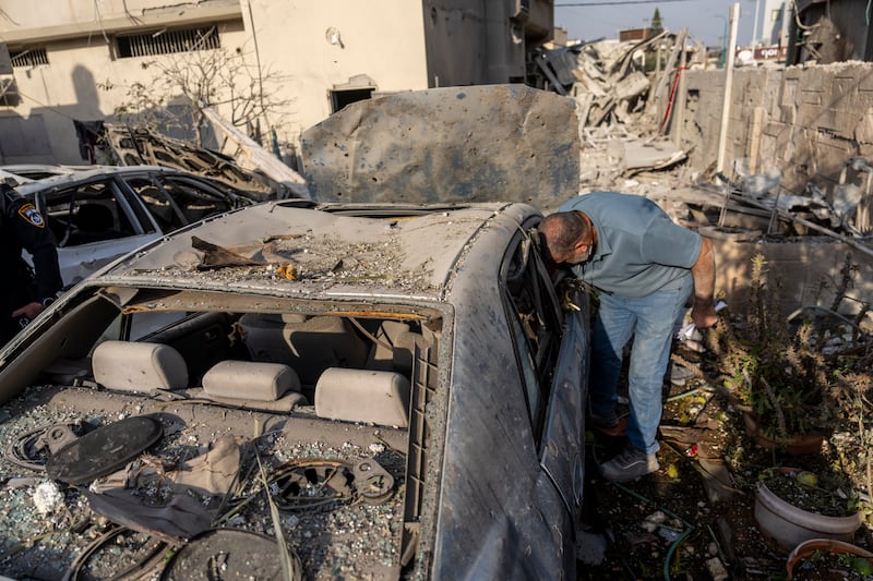 A man surveys damage to his car after projectiles fired from Lebanon hit a home in Tira