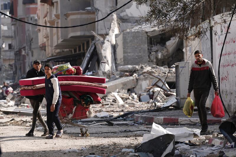 Palestinians walk through destruction in the Nusseirat refugee camp in the Gaza Strip on Tuesday (Adel Hana/AP)
