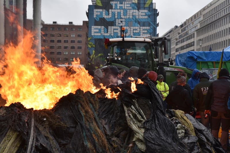 Protesters light fires during a demonstration by farmers in Brussels (Harry Nakos/AP)