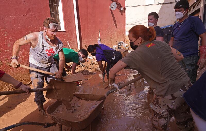 People shovel away mud on Tuesday after floods in Catarroja on the outskirts of Valencia (Alberto Saiz/AP)