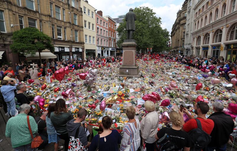 People look at flowers and tributes left in St Ann’s Square in Manchester following the Manchester Arena terror attack