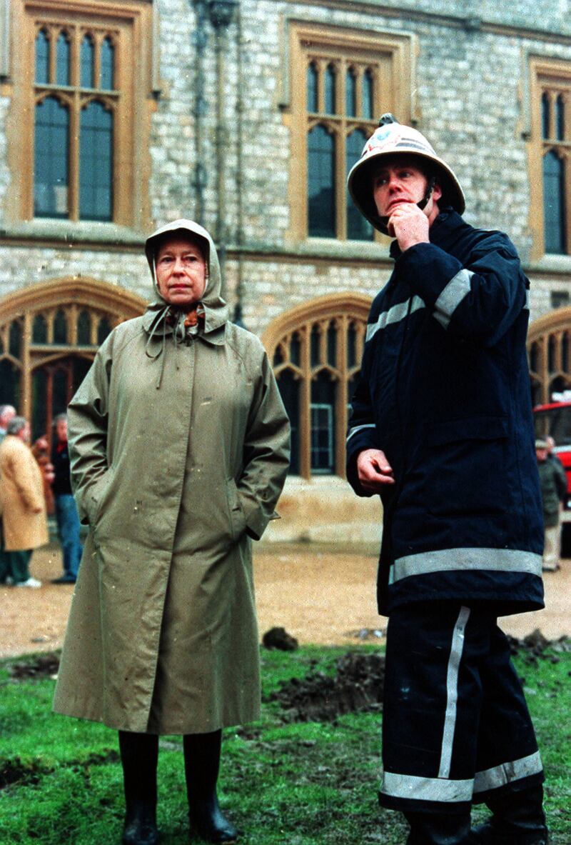 Queen Elizabeth II inspects the ruins of Windsor Castle with a fireman in 1992