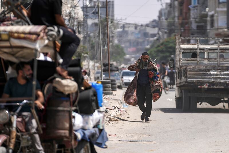 A Palestinian carries his belongings as he evacuates Maghazi refugee camp in Gaza, as part of a mass evacuation ordered by the Israeli military ahead of an operation (Abdel Kareem Hana/AP)