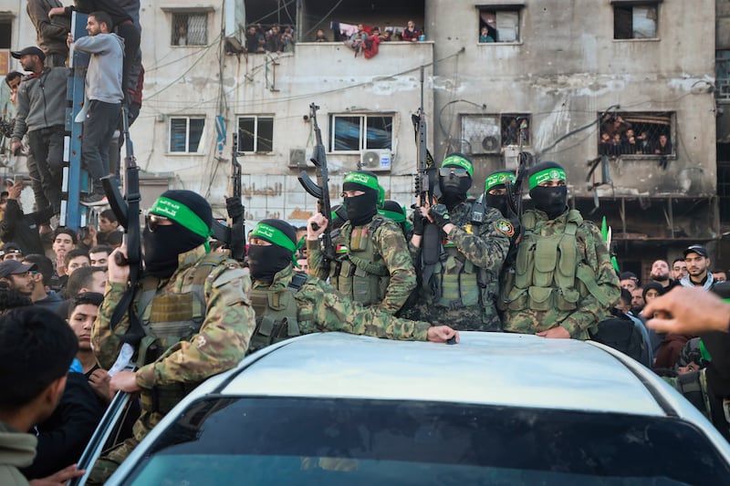 Fighters from the Qassam Brigades, the military wing of Hamas, stand atop a car in Gaza City as Red Cross vehicles manoeuvre to collect Israeli hostages released under a ceasefire agreement between Israel and Hamas (Abed Hajjar/AP)