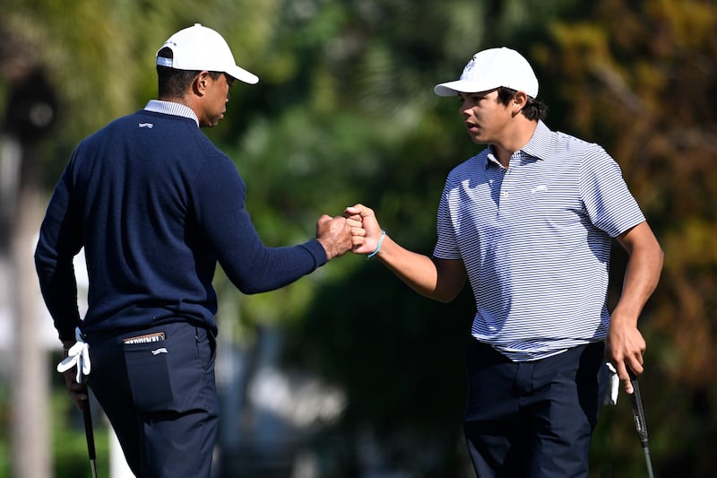 Charlie Woods, right, gets a fist bump from his father, Tiger Woods during the first round of the PNC Championship (Phelan M Ebenhack/AP)